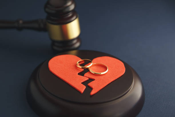wedding rings on the figure of a broken heart from a tree, hammer of a judge on a wooden background. divorce - divorce imagens e fotografias de stock
