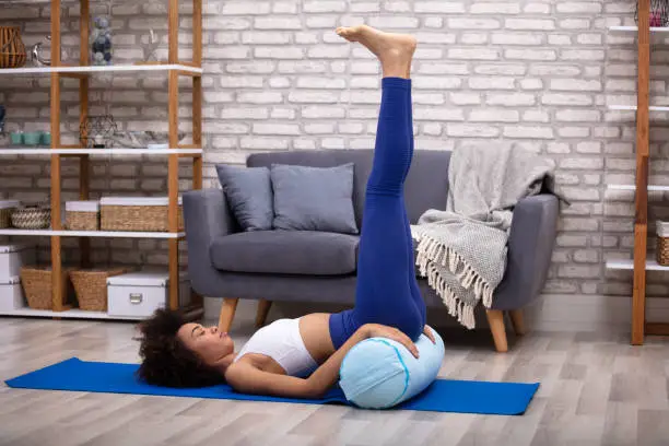 A Young Woman Doing Leg Up Exercise On Yoga Mat In The Living Room