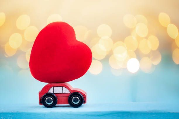 istock Miniature red car carrying a red heart on shine bokeh background. 1094158652