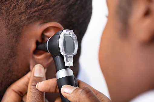 African Doctor Examining Male Patient's Ear With Otoscope
