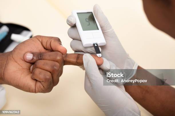 Doctor Checking Patients Blood Sugar Level With Glucometer Stock Photo - Download Image Now