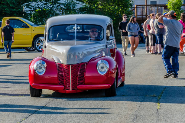 1940 Ford Tudor Sedan Dartmouth, Nova Scotia, Canada - August 10, 2017:  A mildly customized 1940 Ford Tudor enters the  parking lot at the A&W summer weekly Thursday cruise-in, Woodside Ferry Terminal, Dartmouth, Nova Scotia. On a pleasant summer evening people walk among the many classic cars. cruising hot rods stock pictures, royalty-free photos & images