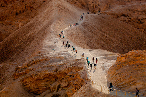 early morning group of tourists climb on the rock of Masada fortress.