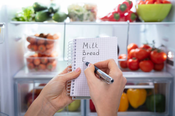 istock Person Writing On Spiral Notepad Near Refrigerator 1094167124