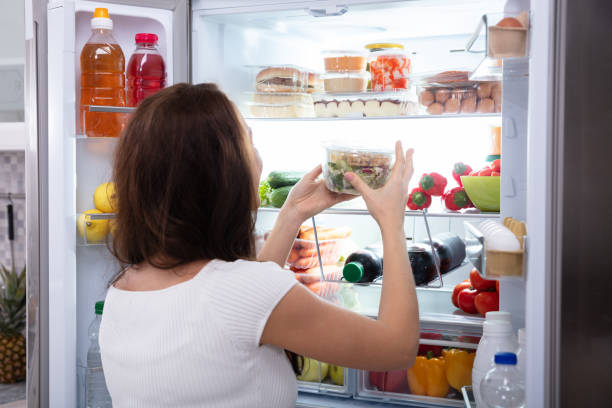 donna che prende cibo dal frigorifero - frigorifero foto e immagini stock