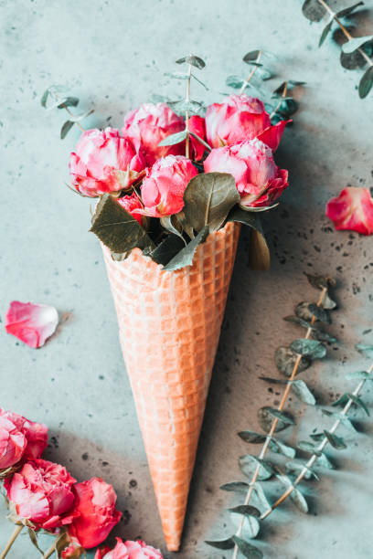 istock Creative minimalist flat lay with waffle cone and pink roses inside it on a grey background. The concept of spring and Valentines day. 1094172990