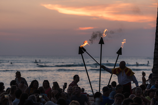 Honolulu, USA – Nov 2, 2017: A man lighting the tiki torches at the free nightly loulou show on Waikiki beach at sunset.