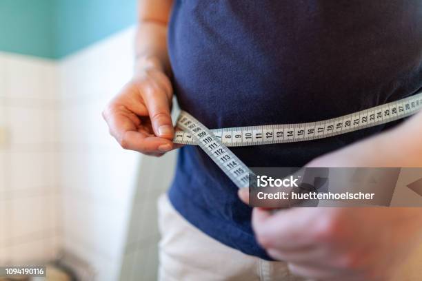 Man Measures Her Abdomen With A Measuring Tape Stock Photo - Download Image Now - Overweight, Men, Abdomen