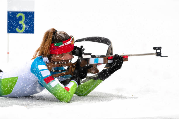 rear view of female biathlon competitor practicing target shooting in snowstorm - biathlon imagens e fotografias de stock