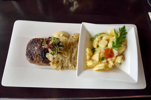 Plate of Berlin meatball (Berliner Boulette) with potato salad and Dijon mustard onions.