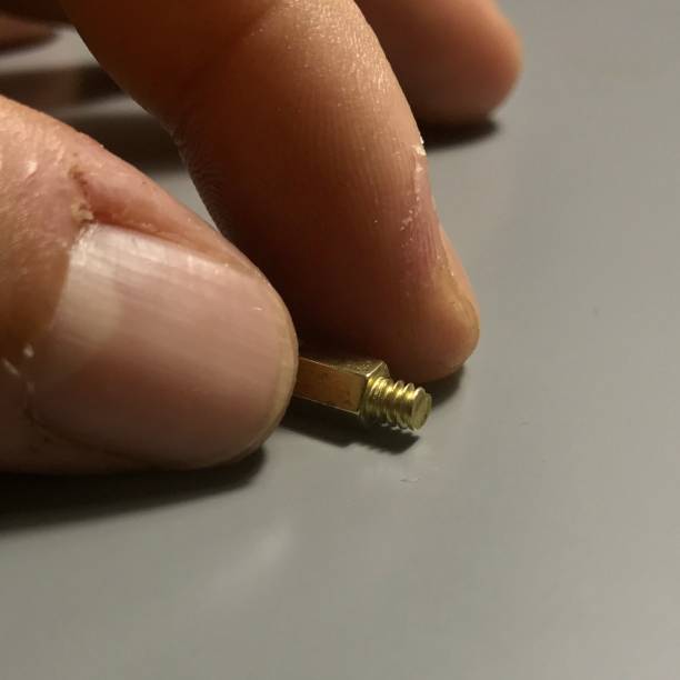 istock TWO FINGERS HOLDING A SMALL YELLOW SCREW 1094210746