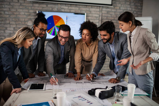 istock Group of multi ethnic architects cooperating while examining blueprints on a meeting in the office 1094212526