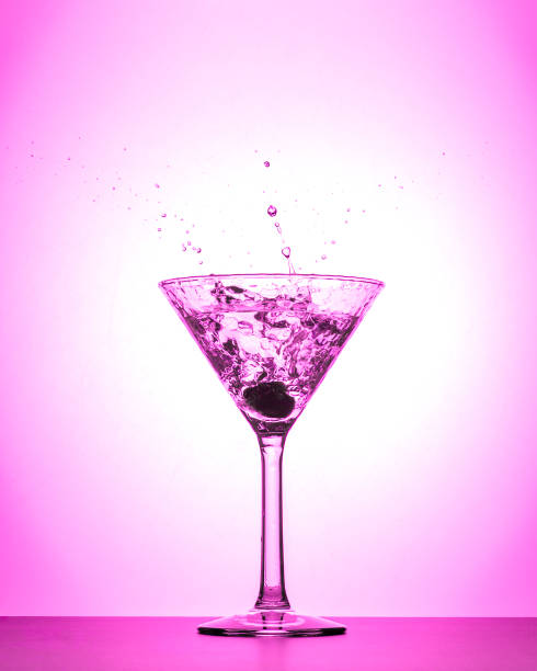 cocktail martini spruzzo di vetro su sfondo sfumato bianco e rosa isolato - vertical studio shot indoors pink foto e immagini stock