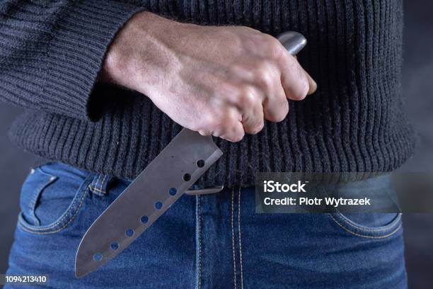 Sharp Steel Knife Held In The Hand Against The Background Of Jeans Trousers Dangerous Poison In The Hands Of An Assassin Dark Background Stock Photo - Download Image Now