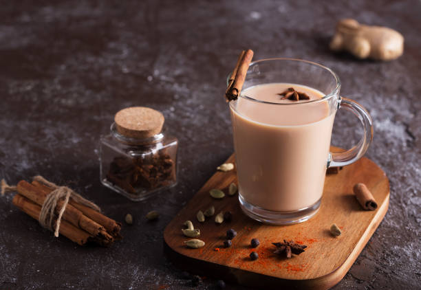 masala chai tee auf dem dunklen hintergrund. indische heißgetränk mit gewürzen - echter teestrauch stock-fotos und bilder