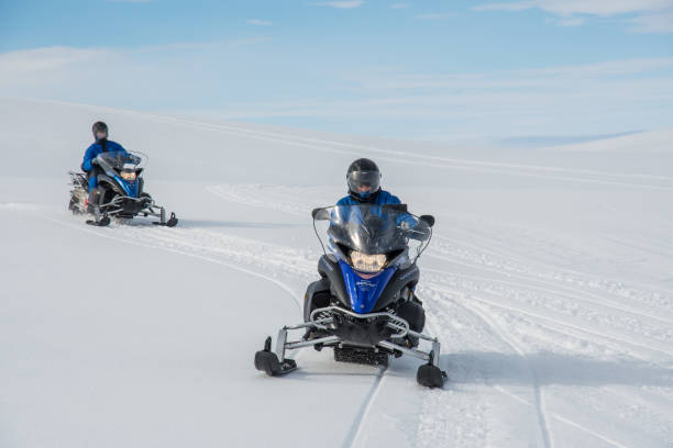 туристы едут на снегоходе на леднике ватнайокулл - snowmobiling adventure snow travel стоковые фото и изображения