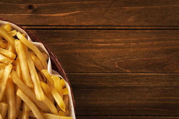French fries in a basket on wooden background stock photo