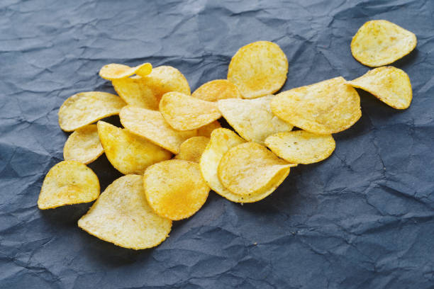 istock Potato chips scattered on a black paper background. 1094248546