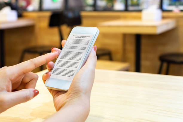 woman reading an e-book online digital smartphone with application mobile device - kindle book reading digital display imagens e fotografias de stock