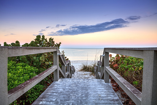 Boardwalk leading down to the white sands along the North Gulf Shore Beach at sunrise in Naples, Florida