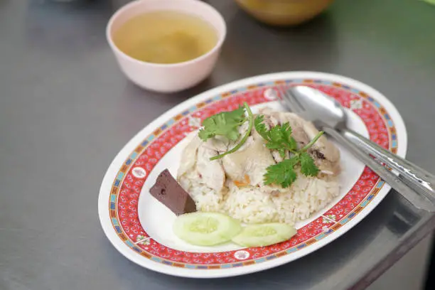 Photo of Steamed chicken and white rice, (Hainanese Chicken Rice) served with soup.