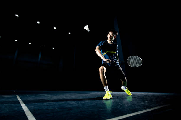 Asian badminton player is hitting in court