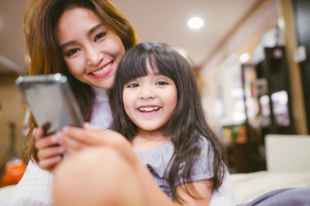 istock kid girl playing smartphone with her mother 1094299718