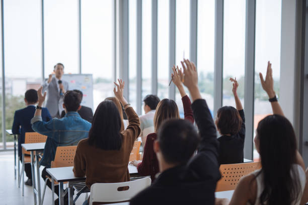 hand raised for Vote and asking at conference seminar meeting room Raised up hands and arms of large group in seminar class room to agree with speaker at conference seminar meeting room press room photos stock pictures, royalty-free photos & images