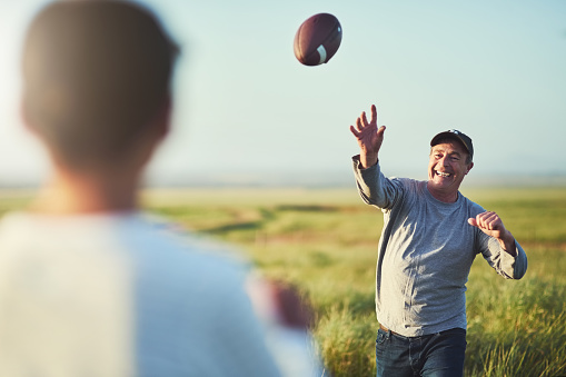 Shot of father throwing a football to his son on a field