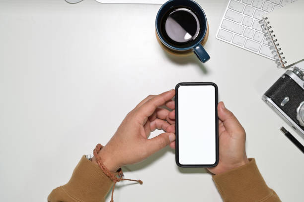 istock Top view man using a mobile smartphone over a workspace desk, Mockup blank screen mobile phone 1094325302