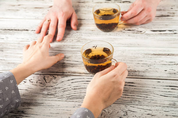 Female and male hands are held on the table. Hands and tea on white textural background copy space and close-up