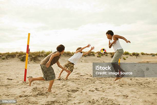 Photo libre de droit de Garçons Jouant Au Football Sur La Plage banque d'images et plus d'images libres de droit de Football - Football, Plage, Jouer