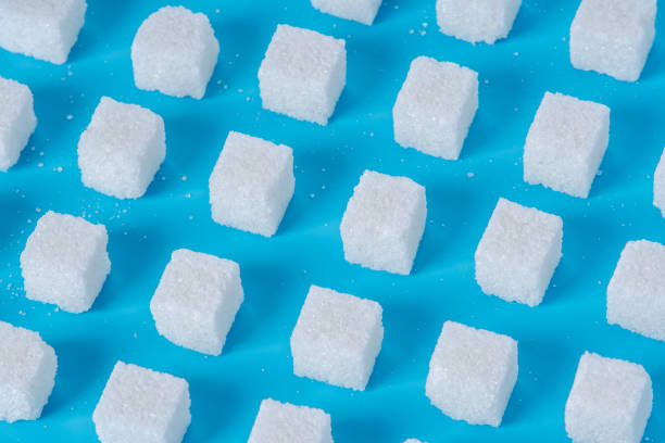 istock Pattern of sugar refined cubes with shadows on a blue background. Concept of harmful ingredient for confectionery 1094331430
