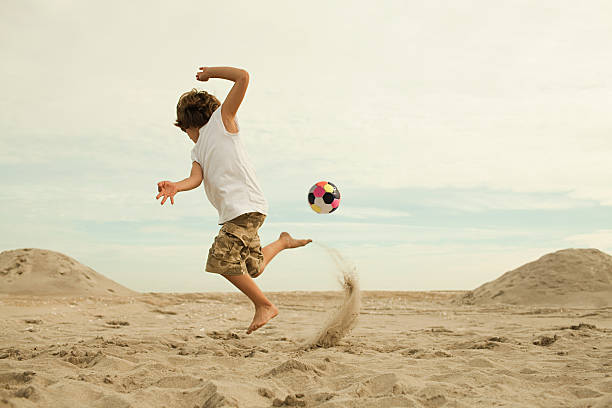 少年キックサッカーのビーチ - beach football ストックフォトと画像