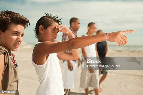 Chłopcy Na Plaży Jeden Chłopiec Wskazując - zdjęcia stockowe i więcej obrazów Dziecko - Dziecko, Przysłaniać oczy, 12-13 lat