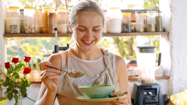 Young happy woman tasting just preparing food in the kitchen. stock photo