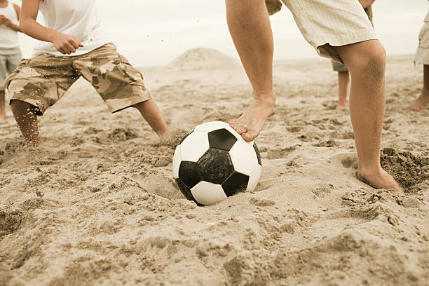 niños jugando al fútbol en playa - beach football fotografías e imágenes de stock