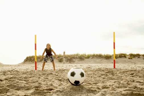 Boys playing football on beach