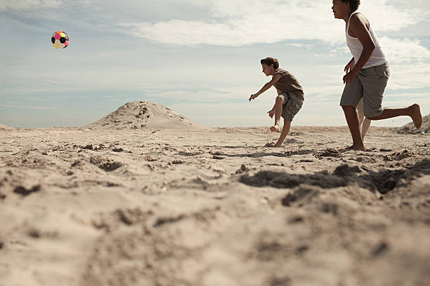 niños jugando al fútbol en playa - beach football fotografías e imágenes de stock