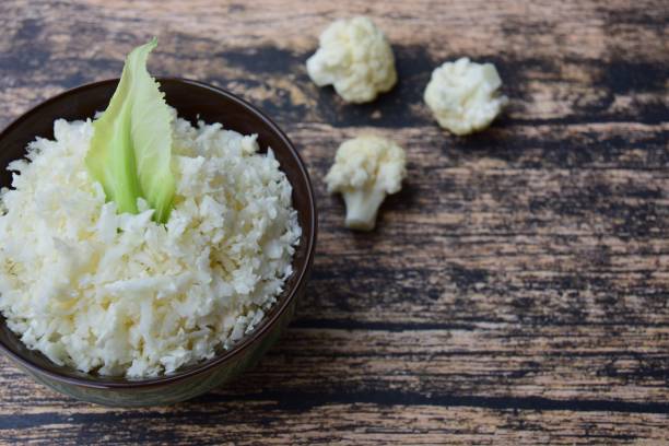 Raw cauliflower rice in a bowl on wooden background