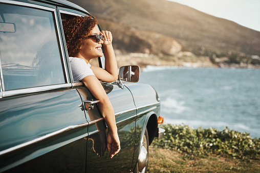 Shot of a young woman enjoying a road trip