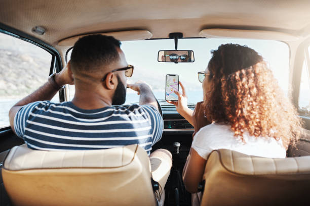 Planning the route to fun Shot of a young couple using gps on their mobile phone during a road trip navigational equipment stock pictures, royalty-free photos & images