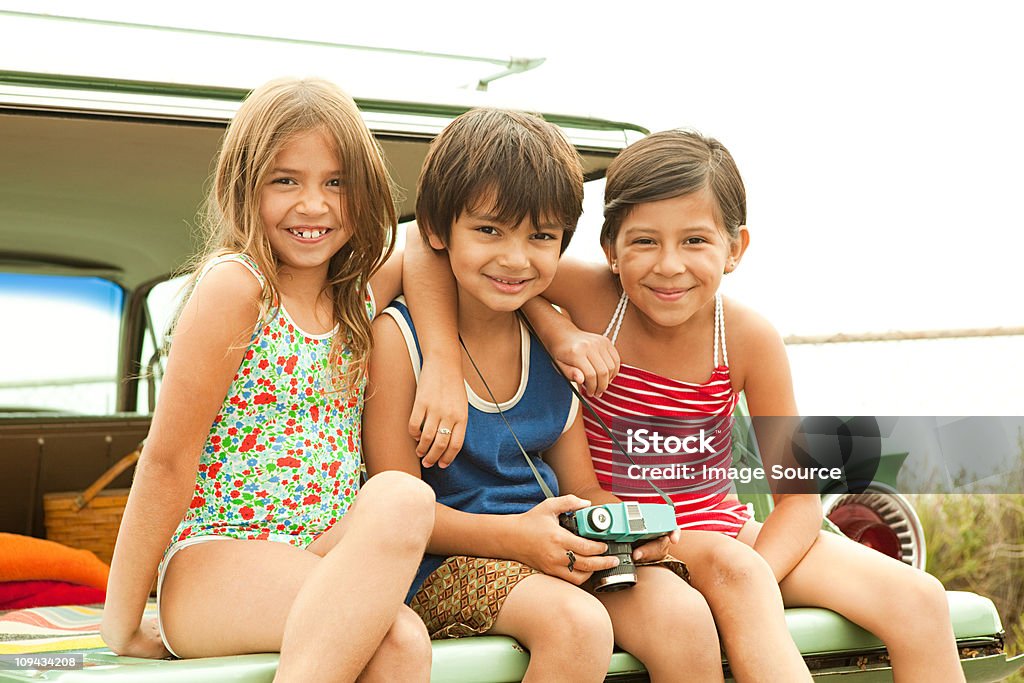 Tres niños ubicado en la parte posterior de la finca automóvil wearing swimwear - Foto de stock de Felicidad libre de derechos