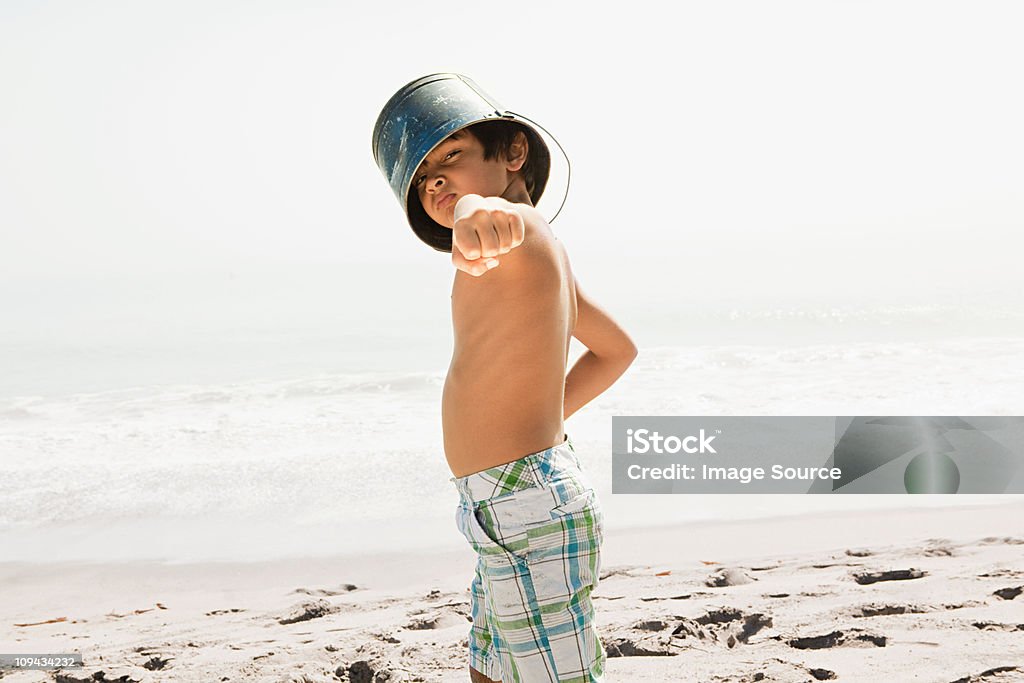 Boy with bucket on head, pointing to camera  Beach Stock Photo