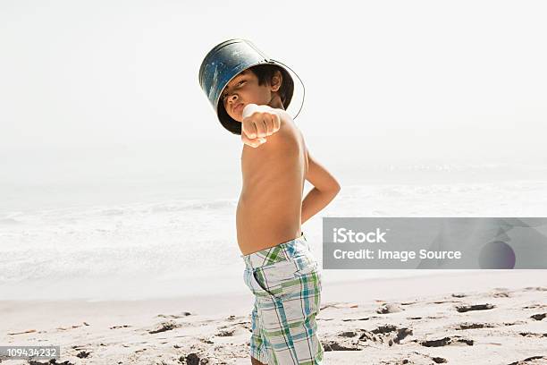 Boy With Bucket On Head Pointing To Camera Stock Photo - Download Image Now - Beach, Boys, Bucket