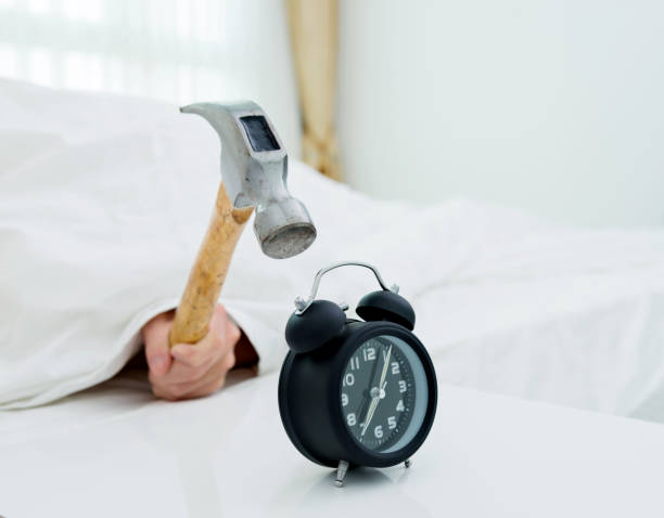 Closeup of man hitting alarm clock with hammer Closeup of man hitting alarm clock with hammer. cross off stock pictures, royalty-free photos & images