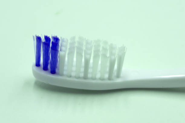 zbliżenie dwóch plastikowych białych szczoteczek do zębów z różowym i niebieskim włosiem na różowym i niebieskim tle. wolne miejsce na kopiowanie. - toothbrush pink turquoise blue zdjęcia i obrazy z banku zdjęć