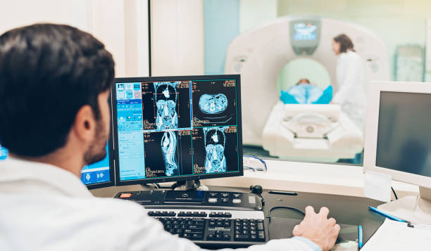 MRI scan technology Doctor looking at a monitor with patient's MRI scan results mri scanner photos stock pictures, royalty-free photos & images