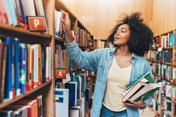 alla ricerca di libri per il progetto dei compiti a casa - book library bookshelf university foto e immagini stock