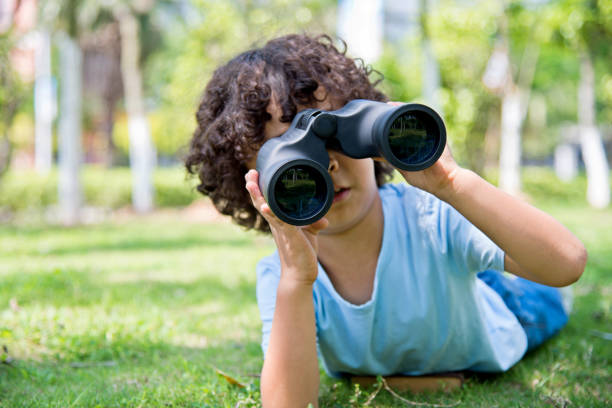 istock Little boy holding a binocular at park 1094358454